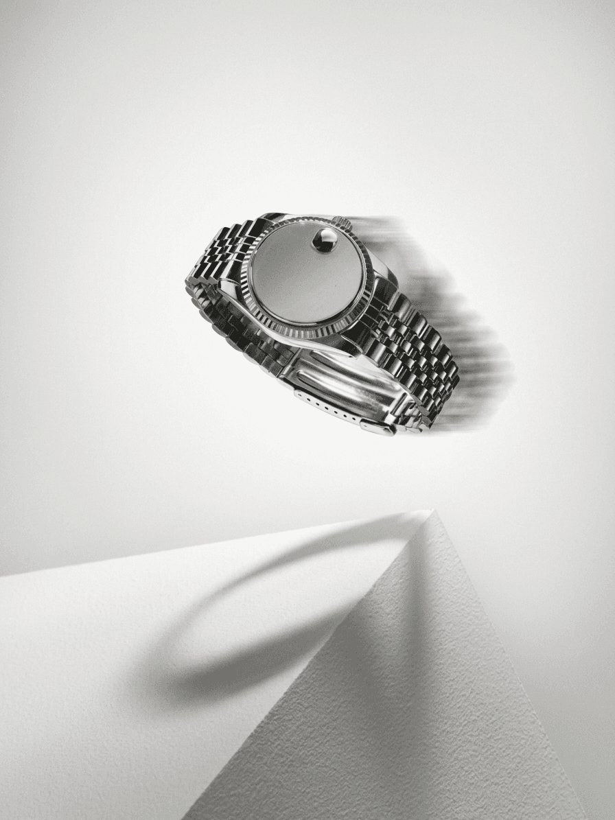 A silver minimalist watch floating against a neutral background.