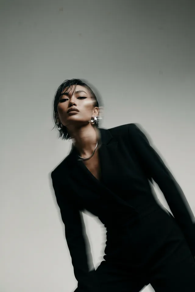 Woman in a black suit with a blurred motion effect in a muted background.