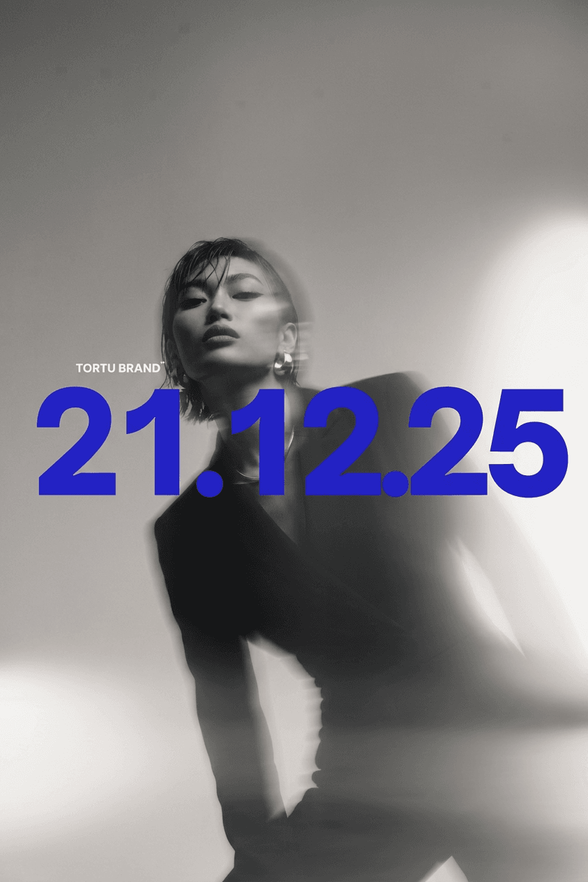A model wearing a black suit in soft focus with blue text '21.12.25'.