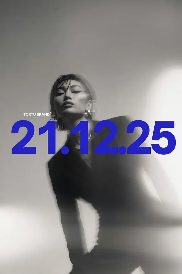 A model wearing a black suit in soft focus with blue text '21.12.25'.