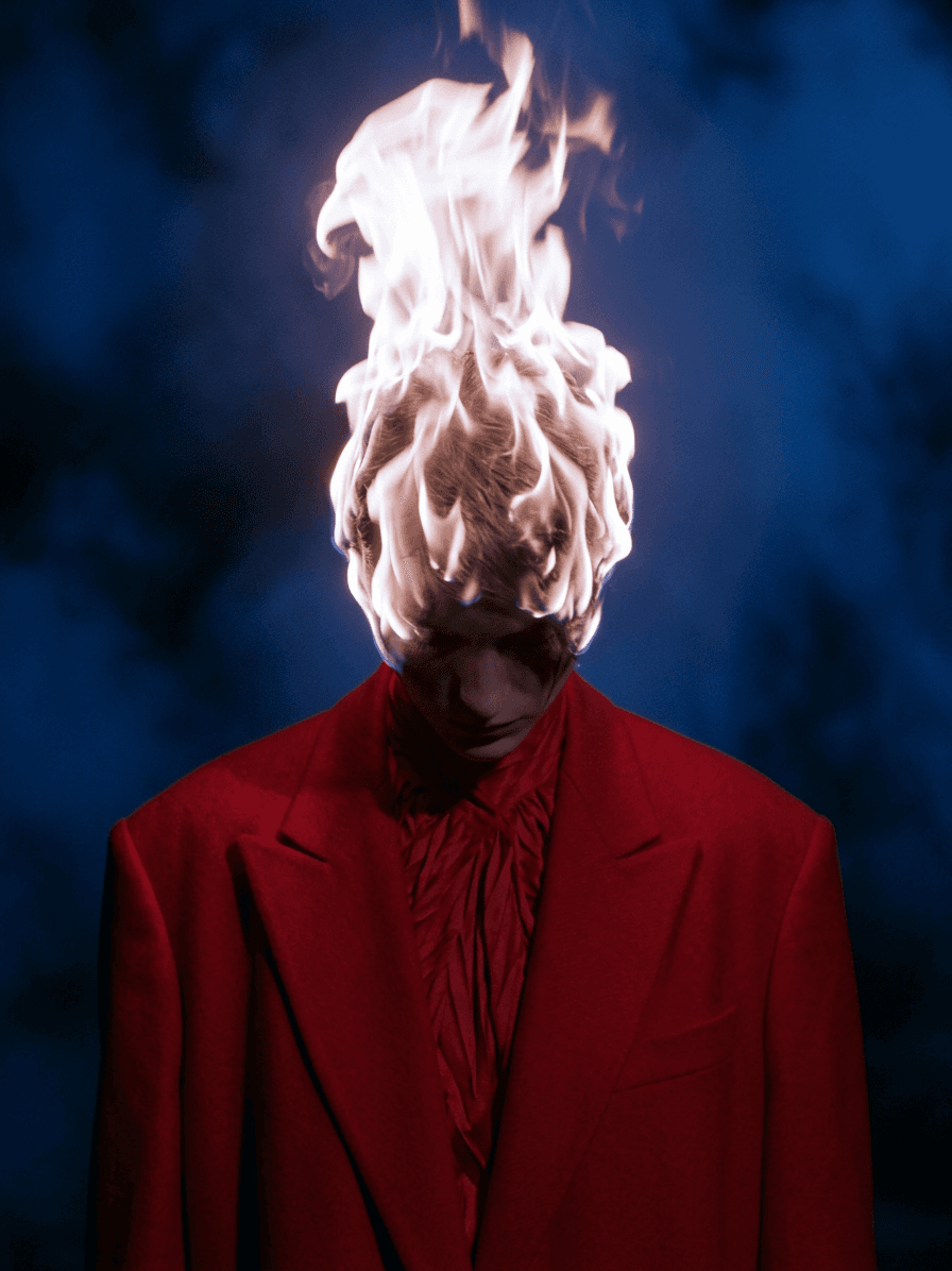 Man wearing a red suit with flames coming from his head, set against a blue background.