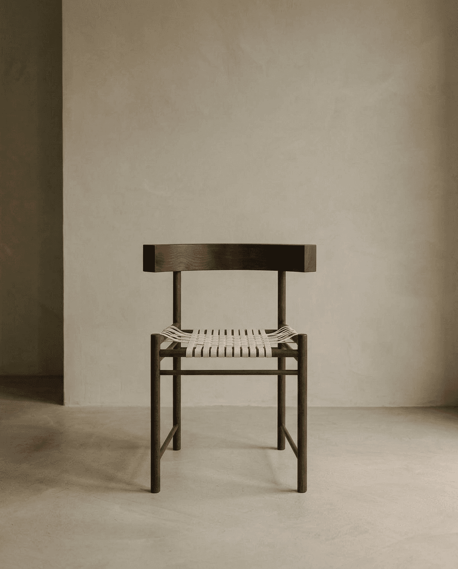 A wooden chair in a minimalist style against a neutral-toned wall.