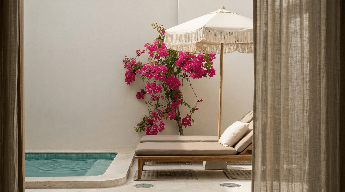 Outdoor space with a sunbed next to a pool, framed by curtains and bougainvillea.