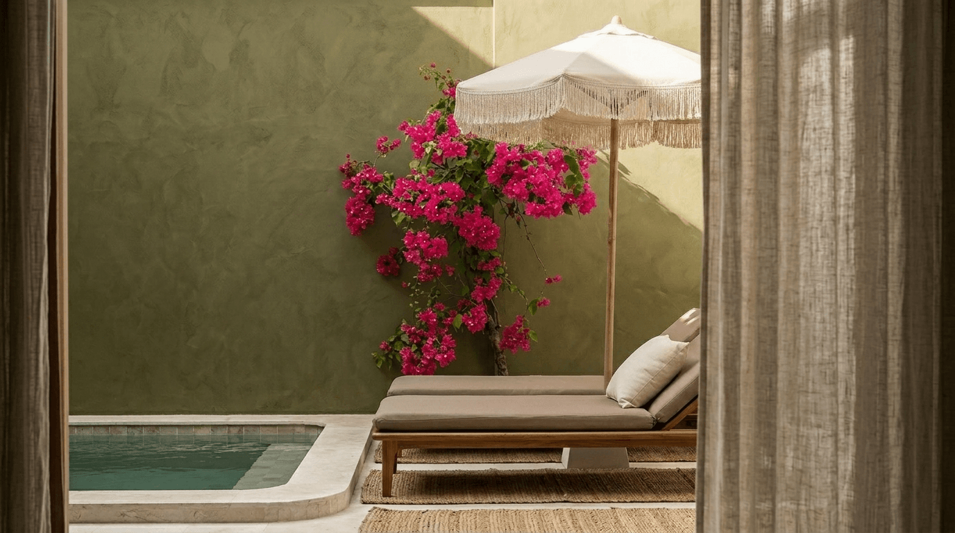 Lounge area beside a pool with curtains and pink bougainvillea.