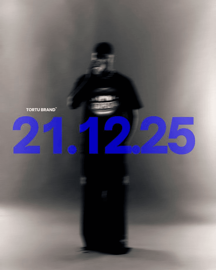 A monochromatic editorial photograph featuring a blurred figure in a black outfit, prominently displaying bold blue